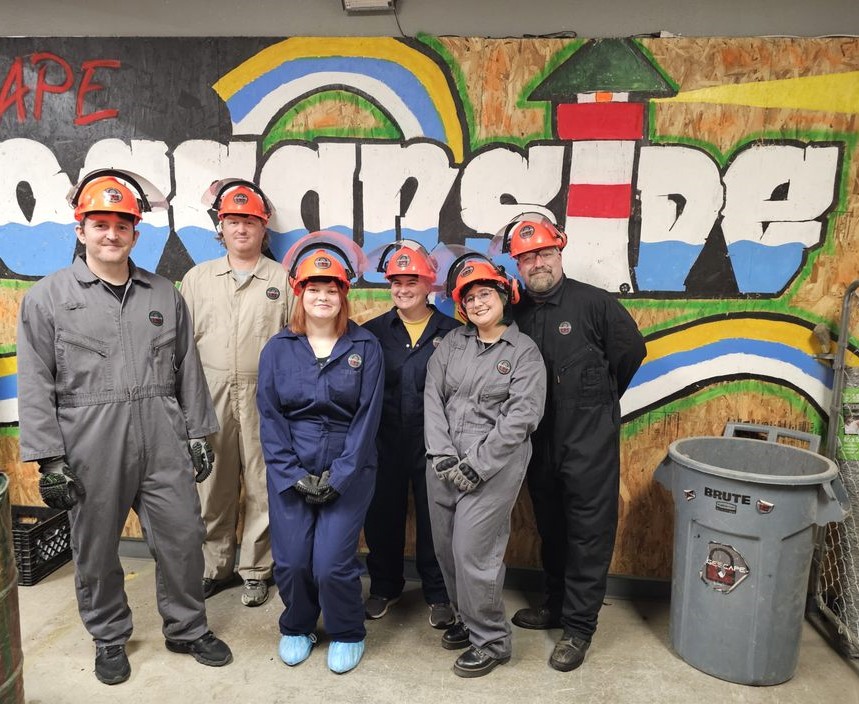 Corporate team wearing protective gear in rage room Oceanside