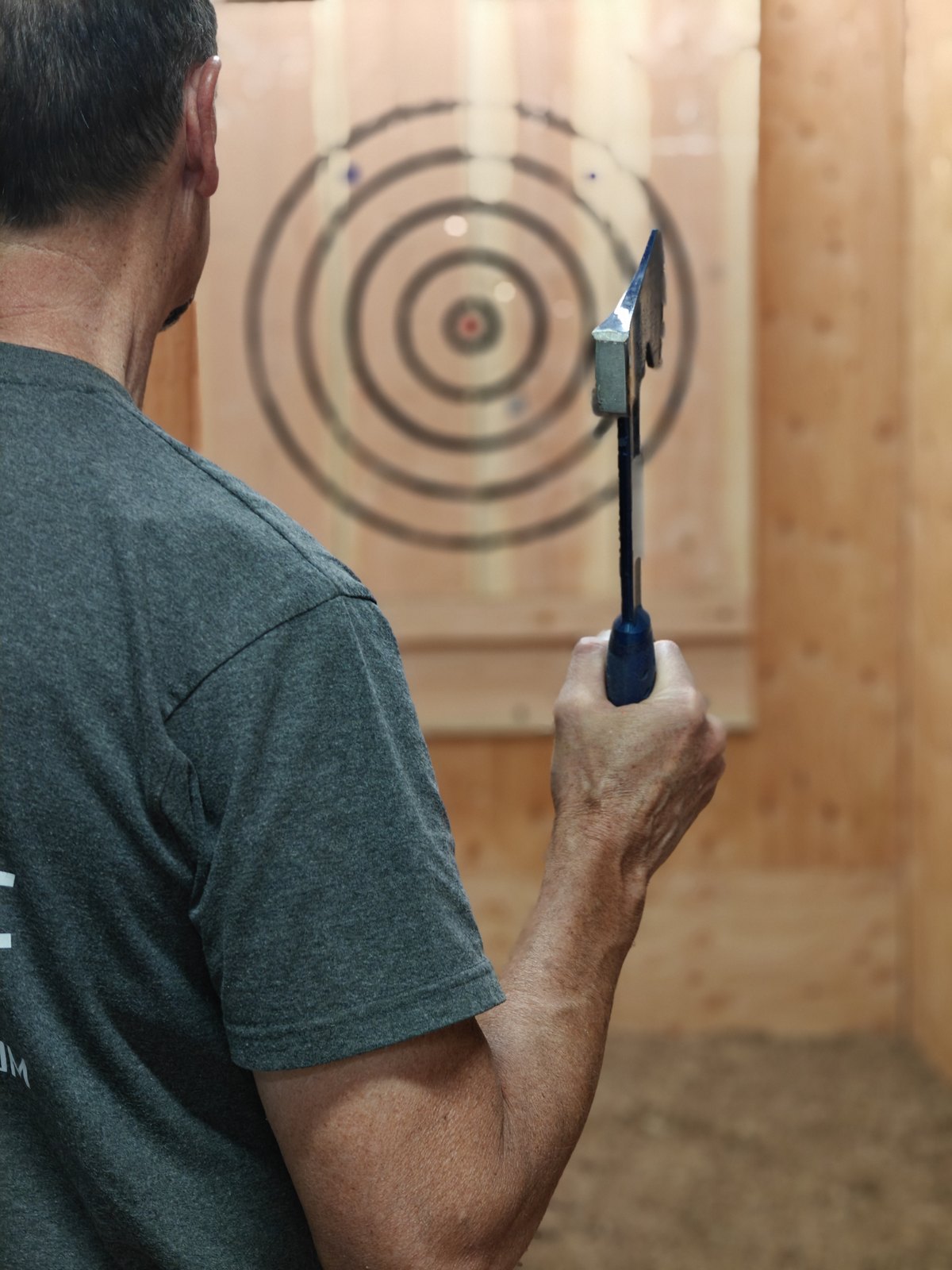 A thrower lining up an axe at a wooden bullseye target in a Chopscape lane